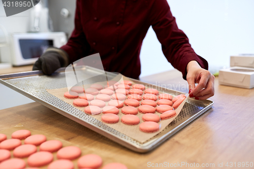 Image of chef with macarons on oven tray at confectionery