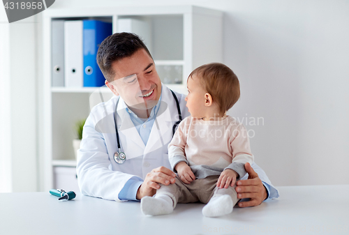 Image of happy doctor or pediatrician with baby at clinic