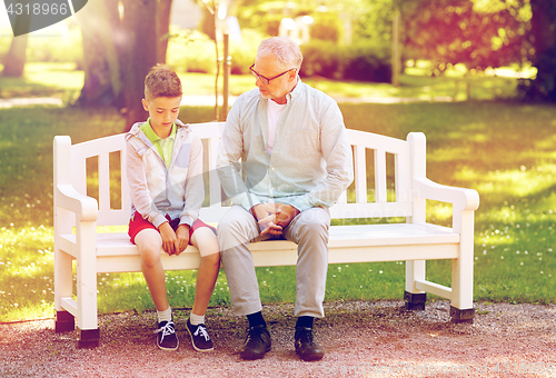 Image of grandfather and grandson talking at summer park