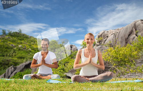 Image of happy couple doing yoga and meditating outdoors