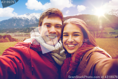 Image of happy couple taking selfie over alps mountains