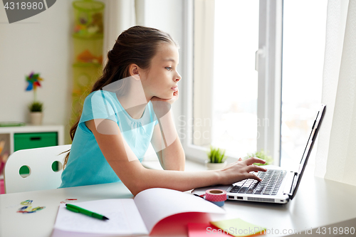 Image of bored girl with laptop and notebook at home