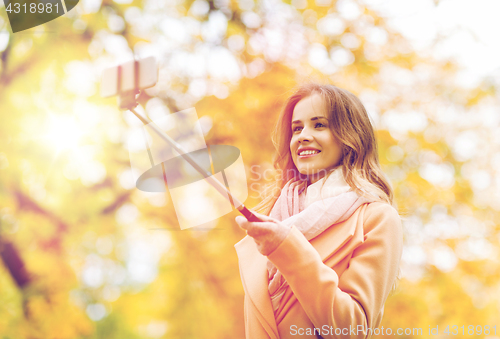 Image of woman taking selfie by smartphone in autumn park