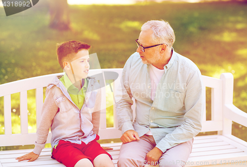 Image of grandfather and grandson talking at summer park