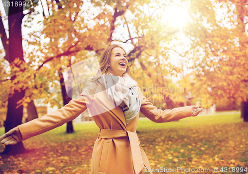 Image of beautiful happy young woman walking in autumn park