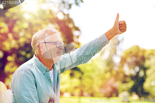 Image of happy senior man showing thumbs up at summer park