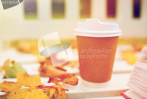 Image of coffee drink in paper cup on bench at autumn park