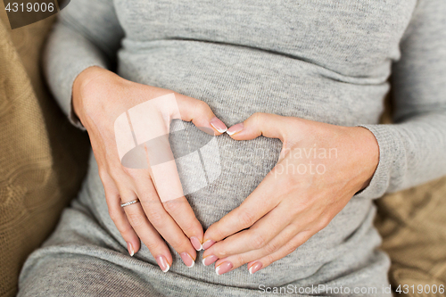 Image of pregnant woman making heart gesture on her belly