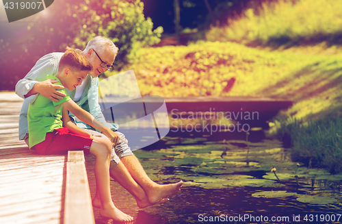 Image of grandfather and grandson sitting on river berth