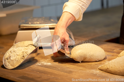 Image of baker portioning dough with bench cutter at bakery