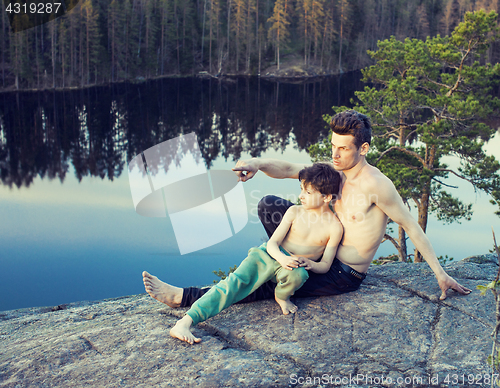 Image of middle age man with little cute son doing sport yoga on the top of the mountain together, happy family lifestyle people outdoor, summer wild nature for training 