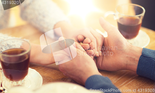 Image of close up of couple holding hands at restaurant