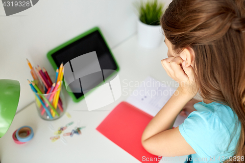 Image of girl with tablet pc writing to notebook at home