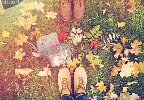 Image of feet in boots with rowanberries and autumn leaves