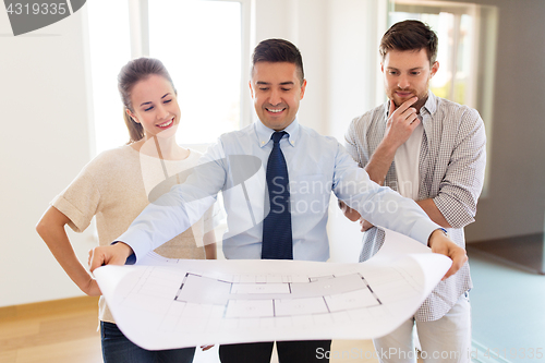 Image of realtor showing blueprint of new home to couple