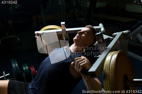 Image of man doing chest press on exercise machine in gym