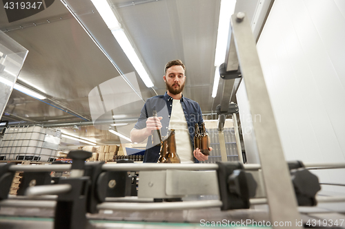 Image of men with bottles on conveyor at craft beer brewery