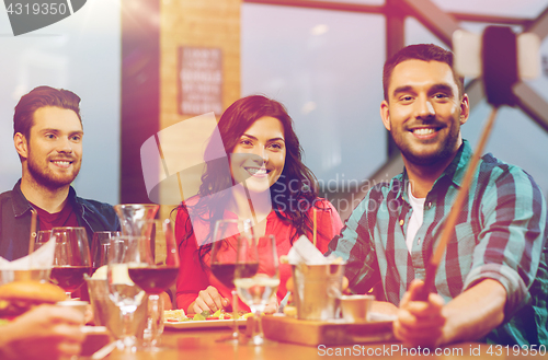 Image of friends taking selfie by smartphone at restaurant