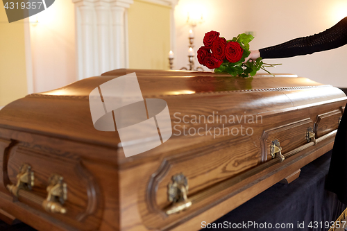 Image of woman with red roses and coffin at funeral
