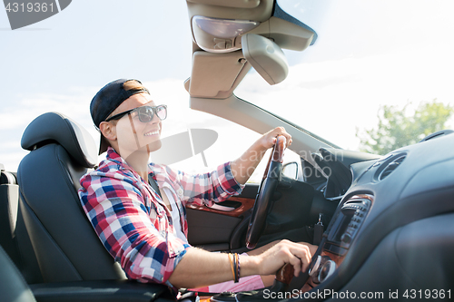 Image of happy young man driving convertible car