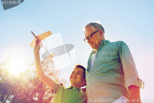 Image of senior man and boy with toy airplane over sky