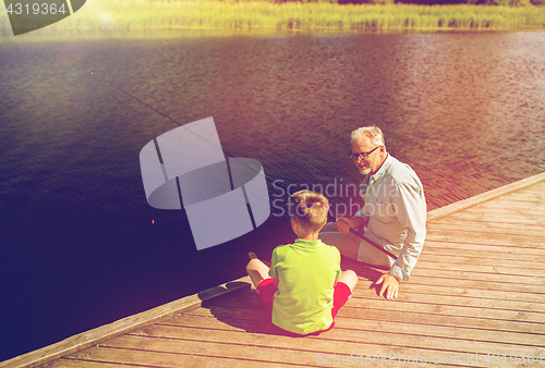 Image of grandfather and grandson fishing on river berth