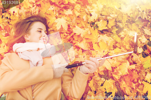 Image of woman on autumn leaves taking selfie by smartphone