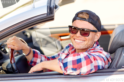 Image of happy young man in shades driving convertible car