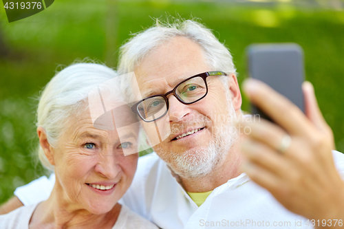 Image of senior couple with smartphone taking selfie in summer