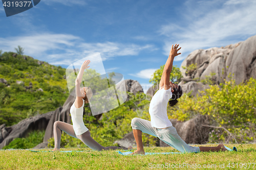 Image of couple making yoga in low lunge pose outdoors