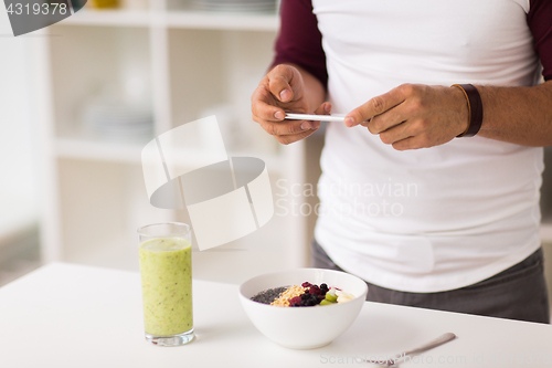 Image of man with smartphone having breakfast at home