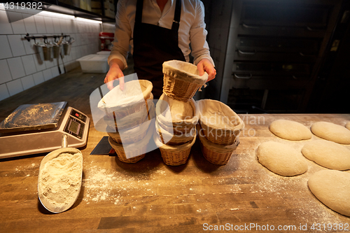 Image of baker with baskets for dough rising at bakery