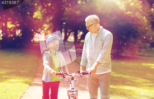 Image of grandfather and boy with bicycle at summer park