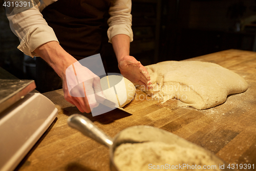 Image of baker portioning dough with bench cutter at bakery