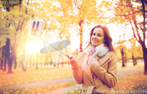 Image of woman taking selfie by smartphone in autumn park