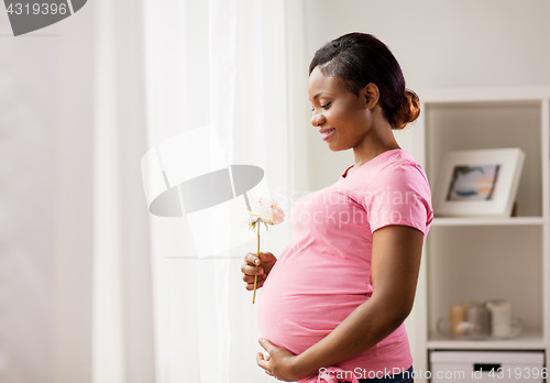 Image of happy african american pregnant woman with flower