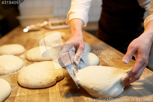 Image of baker portioning dough with bench cutter at bakery