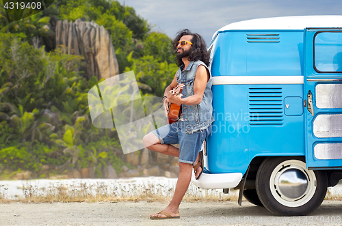 Image of hippie man playing guitar at minivan car on island