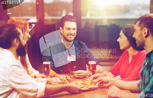 Image of friends eating pizza with beer at restaurant