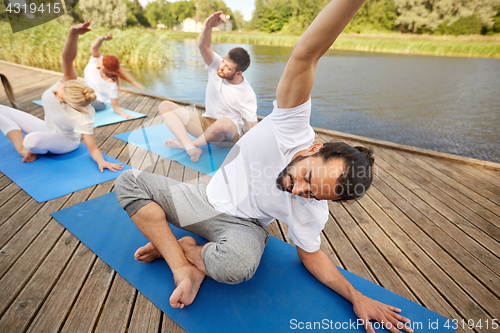 Image of group of people making yoga exercises outdoors