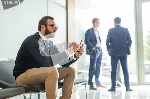 Image of Businessman using smart phone while sitting in waiting room.