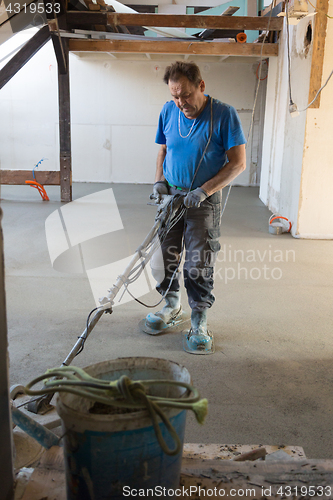 Image of Laborer polishing sand and cement screed floor.