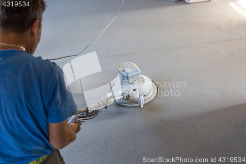 Image of Laborer polishing sand and cement screed floor.
