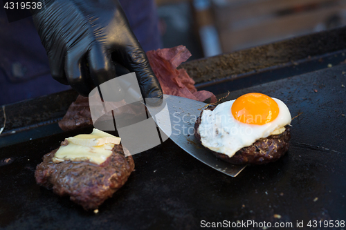 Image of Chef making beef burgers outdoor on open kitchen international food festival event.