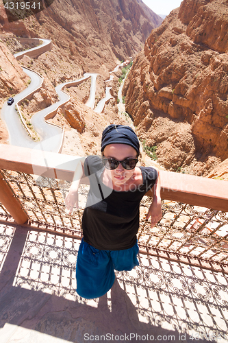 Image of Image of female tourist relaxing on a terrace ovelooking winding road in Dades Valley, Atlas mountains, Morocco.