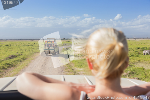 Image of Woman on african wildlife safari observing nature from open roof safari jeep.