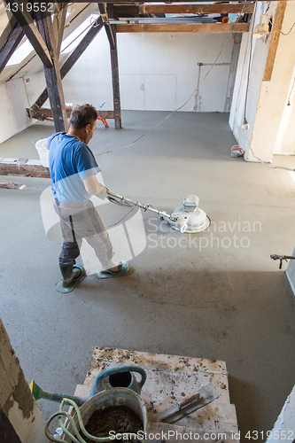 Image of Laborer polishing sand and cement screed floor.