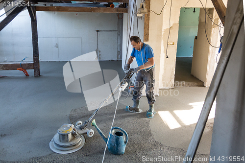 Image of Laborer polishing sand and cement screed floor.