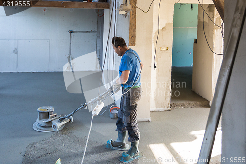 Image of Laborer polishing sand and cement screed floor.