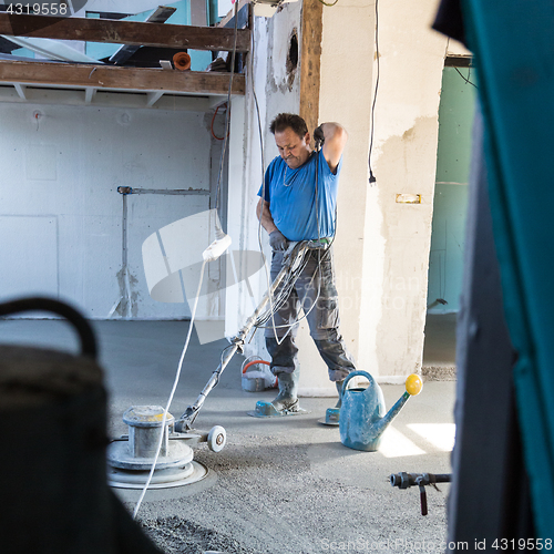 Image of Laborer polishing sand and cement screed floor.